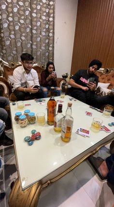 people sitting around a table with drinks and cookies on it