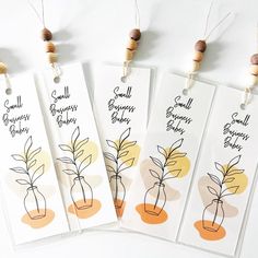 four tags with small plants on them hanging from strings