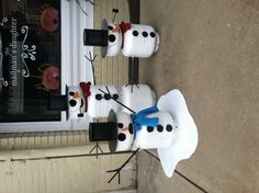 three snowmen with hats and bow ties are standing in front of a store window