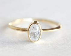 a gold ring with a white diamond in the center and a thin band around it