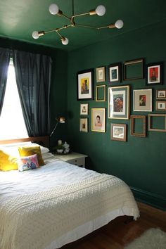 a bedroom with green walls and pictures on the wall above the bed in front of it