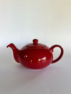 a red teapot sitting on top of a white table