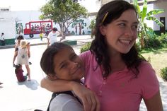 a woman holding a child in her arms while standing next to other people on the street