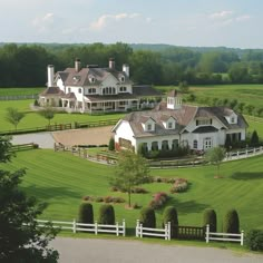 an aerial view of a large white house in the middle of a lush green field