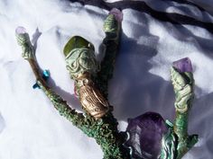 an owl figurine sitting on top of a tree branch next to some crystals