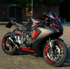 a red and black motorcycle parked on top of a brick road