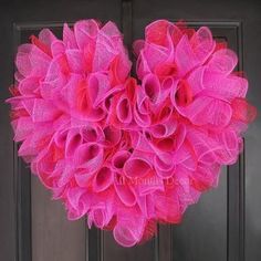 a heart shaped wreath hanging on the front door with pink tulle attached to it