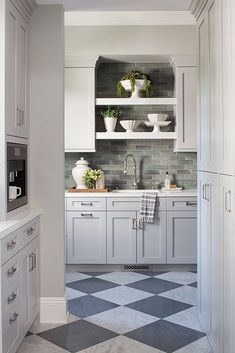 a kitchen with white cabinets and black and white checkerboard flooring in it