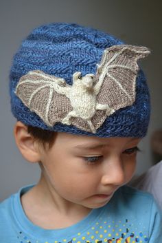 a young boy wearing a knitted hat with a bat on it's side