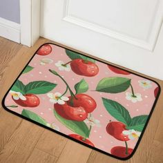 a pink door mat with cherries and leaves on it, next to a white door