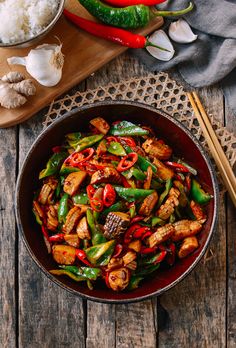 a pan filled with stir fry vegetables next to chopsticks on a wooden table