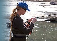 a woman standing in the water while fishing