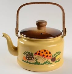 a yellow tea pot with a wooden handle and ladybug painted on the side