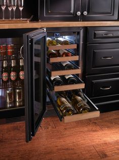 an open wine cooler in a kitchen with lots of bottles