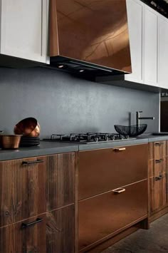 a modern kitchen with wooden cabinets and black counter tops, along with white cupboards