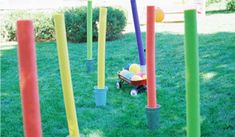 an assortment of colorful plastic poles in the grass with balls and tees on them