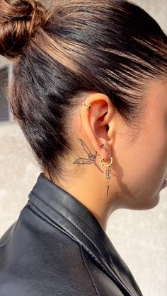 the back of a woman's head with ear piercings on her left side