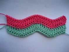 a crocheted pink and green eye mask sitting on top of a white surface