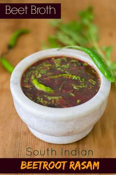 the bowl is filled with soup and garnished with green leaves on top, sitting on a wooden surface