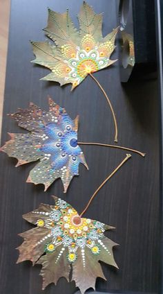 three metal leaf decorations on a wooden table