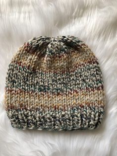 a multicolored knitted hat laying on white fur