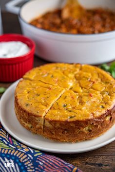 a cake sitting on top of a white plate next to a bowl of chili and sour cream