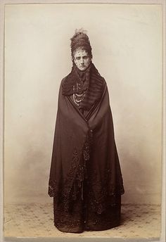 an old fashion photo of a woman wearing a black dress and shawl with lace on it