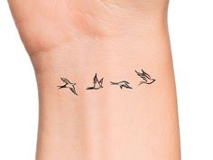 a small wrist tattoo with birds flying in the sky on it's left side