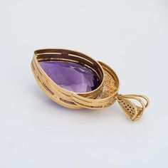 Finely detailed vintage amethyst & diamond pendant crafted in 14 karat yellow gold (circa 1970s).    Pear cut amethyst measures 36mm x 26mm (estimated at 65 carats), accented with 56 small round brilliant cut diamonds totaling an estimated 0.56 carats (estimated at I-J color and SI2-I2 clarity. The amethyst is in good condition and free of cracks or chips.    The large pendant is set with a rich royal purple amethyst, checkerboard faceted to draw maximum sparkle. The bale measures 7mm wide and can accommodate a medium to thick chain. A great statement piece with a sleek pear shaped design.    The pendant is in very good condition and was lightly cleaned and polished.    Particulars:    Weight: 26.4 grams    Stones: Pear cut amethyst measures 36mm x 26mm (estimated at 65 carats), accented w Yellow Gold Pear-shaped Amethyst Jewelry, Pear-shaped Amethyst Jewelry In Yellow Gold, Luxury Purple Pear-shaped Jewelry, Red Pendants, Blue Pendant, Royal Purple, Amethyst Pendant, Modern Pendant, Silver Pendants