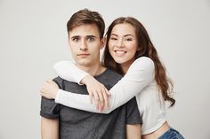 a young man and woman embracing each other with their arms around the shoulders stock photo