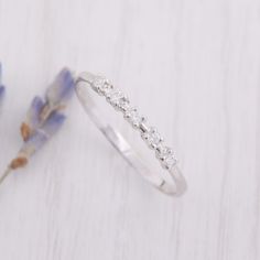 a white gold wedding band with three diamonds on the side, and a blue flower in the background