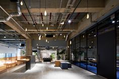 an empty room with benches, tables and lights hanging from the ceiling in front of glass windows