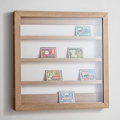 a wooden framed display case with various books on the bottom shelf and below it is a white wall