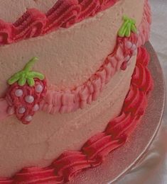 there is a pink cake with strawberry decorations on it