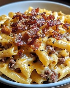 a bowl filled with macaroni and cheese covered in bacon sitting on top of a wooden table