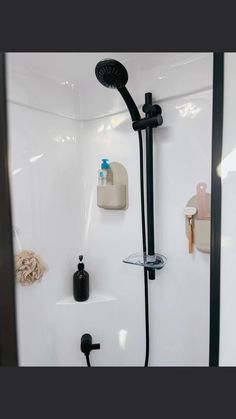 the shower head is connected to the wall with black faucet and soap dispenser