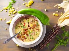 a bowl filled with soup next to corn on the cob and a green pepper