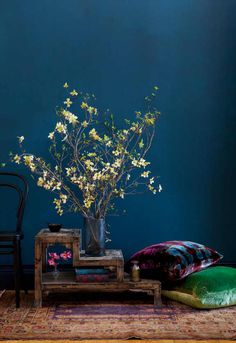 a vase with white flowers sitting on top of a table next to pillows and a chair