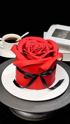 a red rose sitting on top of a white plate next to a cup of coffee