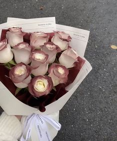 a person holding a bouquet of roses in their hand on the street with other flowers