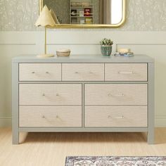 a dresser with drawers and a mirror above it in a room that has a rug on the floor