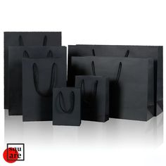 black paper bags with handles are lined up against the white background and one is empty