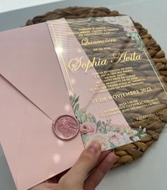 a person holding a pink envelope with a wax stamp on it and a gold foil seal