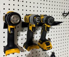 three yellow and black tools hanging on a pegboard