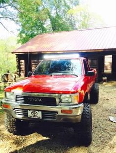 a red pick up truck parked in front of a cabin