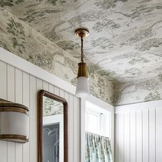 a bathroom with a mirror, sink and wallpaper on the ceiling in it's corner