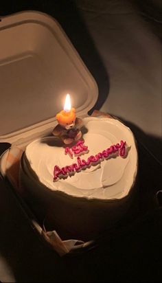 a birthday cake with a lit candle on it and the words happy anniversary written in frosting