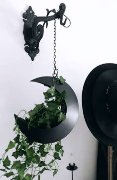 a hat hanging from the side of a wall next to a clock and planter