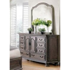 an ornate dresser with mirror and potted plants on it in front of a window