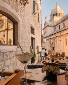 an outdoor dining area with tables, chairs and wine glasses on the table in front of it